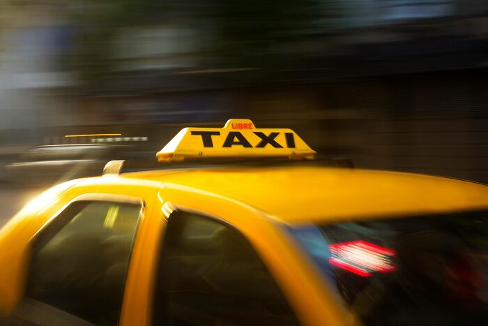 Yellow taxi in motion on a city street illustrating frustration with over-the-top workplace rules and regulations.