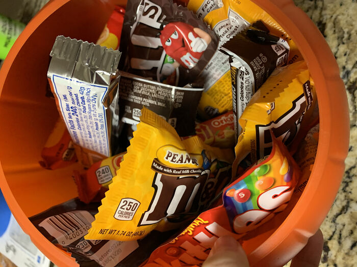 Orange bucket filled with assorted Halloween candy, showcasing a common Halloween fail with overly packaged treats.