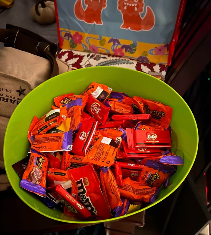 Bright green bowl filled with assorted Halloween candy showing a Halloween fail with excessive wrappers and clutter.