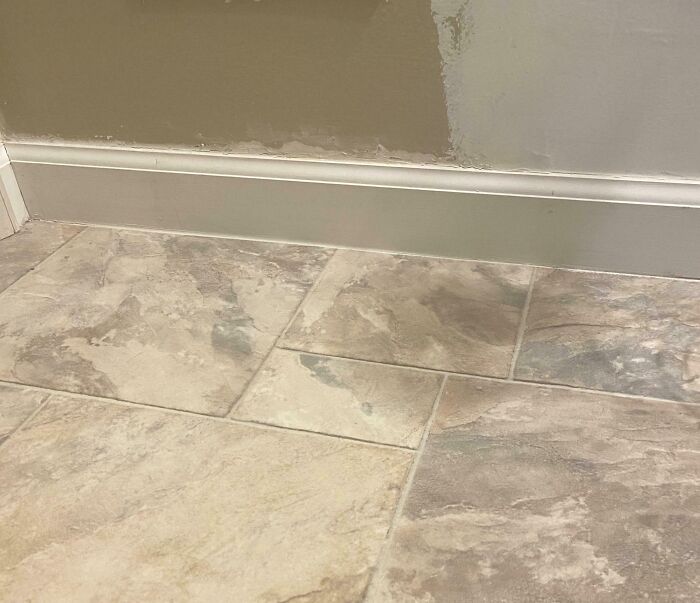 Unevenly painted wall with a patchy color next to a beige tiled floor showing a Halloween fail in home decor.