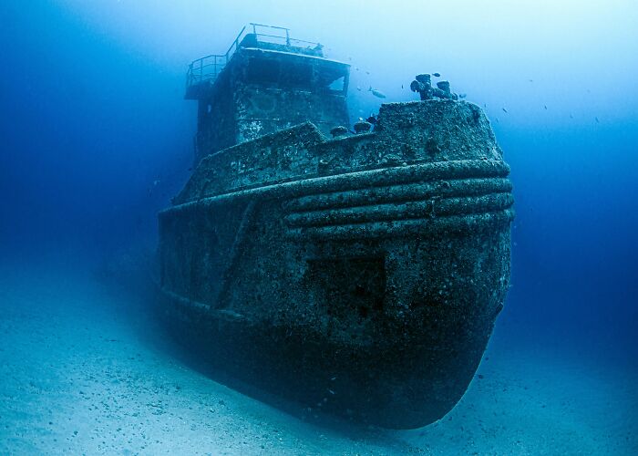Sunken shipwreck covered in marine growth resting on the ocean floor showcasing weird and fascinating things in the ocean.