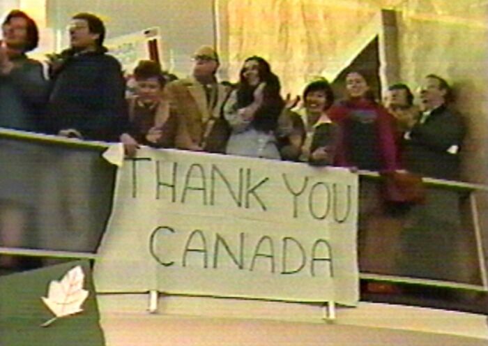 Group of people holding a thank you Canada sign, showcasing a wild and weird moment from the fascinating 1980s era.