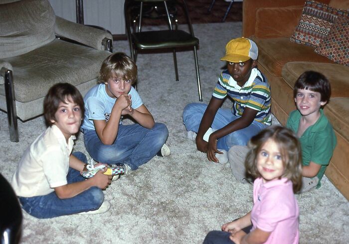Group of kids sitting on carpet in 1980s living room, showcasing wild, weird, and wonderful moments from the decade.