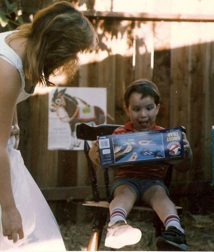 Young boy excitedly holding a Ghost Trap toy while a woman watches, capturing wild and wonderful 1980s moments.