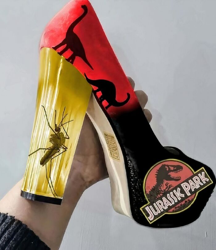 High heel shoe with a preserved insect in the heel and Jurassic Park dinosaur silhouettes, a confusing image that gets weirder.
