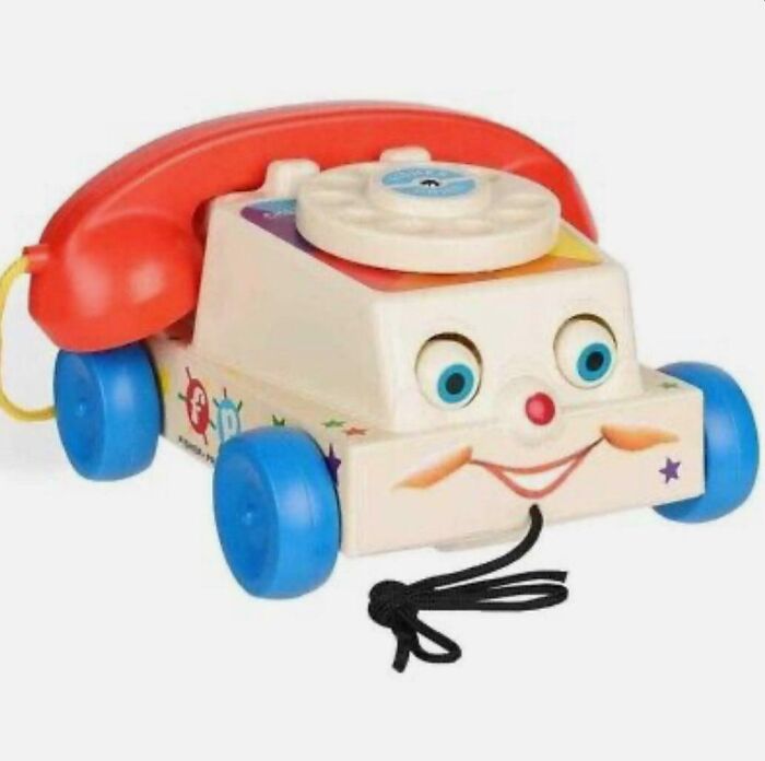 Vintage Fisher Price rotary toy phone with wheels and a smiling face, a nostalgic item that makes people feel very old.