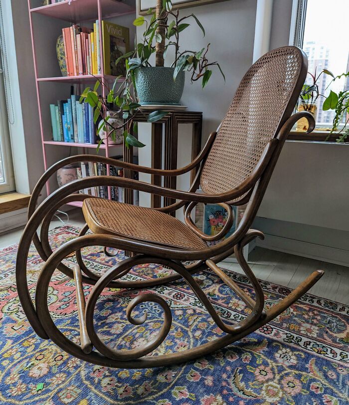 Vintage wooden rocking chair with woven seat and backrest, a lucky thrift store shopping jackpot find in cozy room.