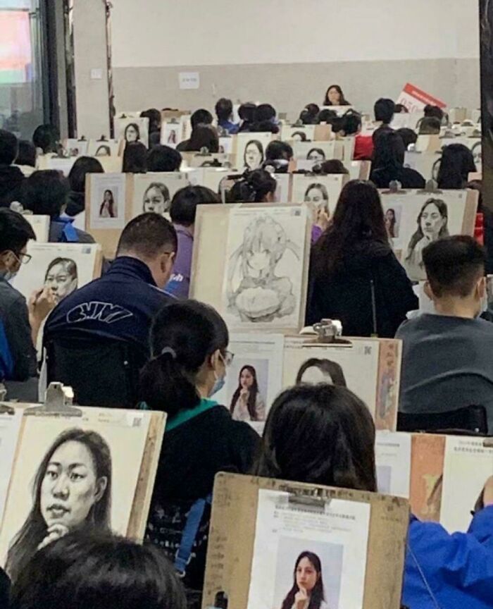 Students focused on drawing detailed portrait pictures in a crowded classroom setting for art practice.