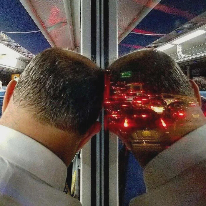 Man leaning head against bus window reflecting a traffic jam, illustrating funny pictures that go hard and provoke laughter.