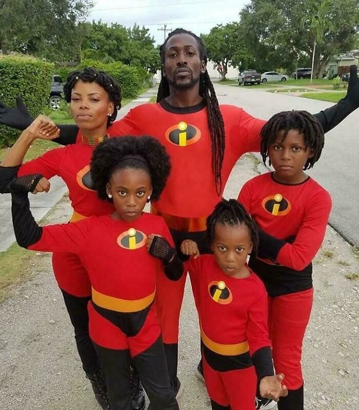 Family wearing matching superhero costumes posing outdoors showing strength in funny people chuckling pictures that go hard
