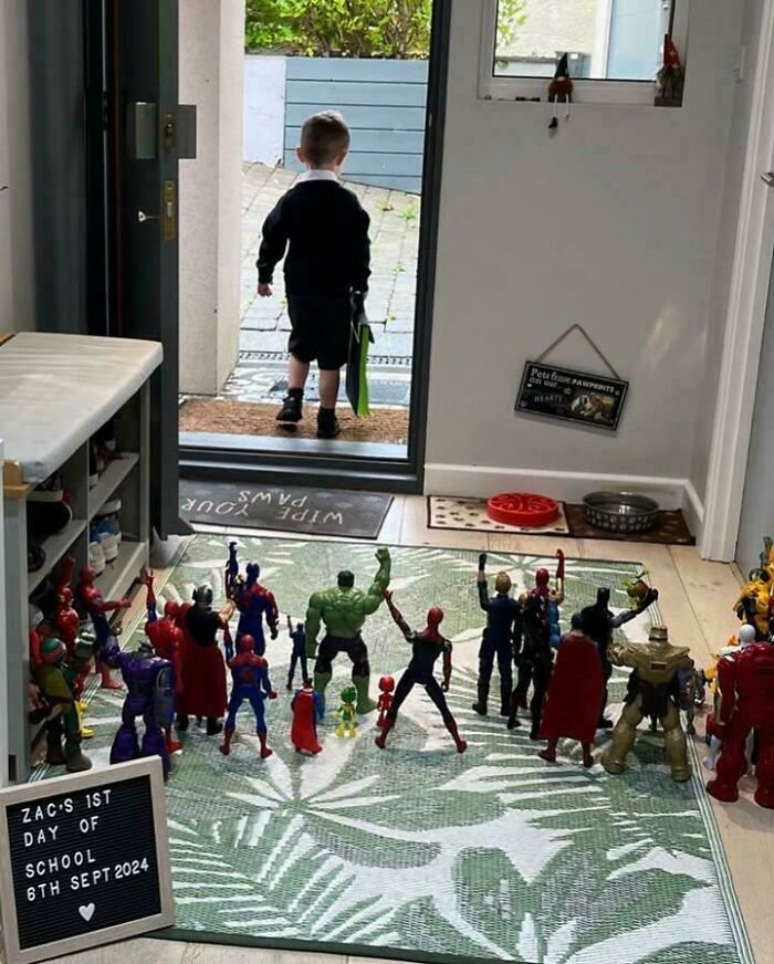 A child walking out the door while toy superheroes stand in formation cheering, capturing funny pictures that go hard.