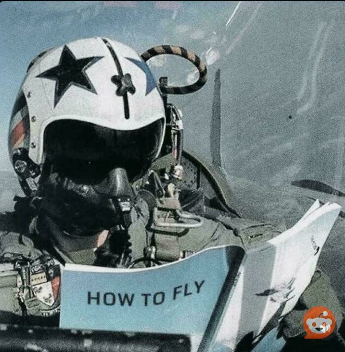 Pilot in cockpit wearing helmet with star logo reading a humorous how to fly manual, a funny picture that goes hard.