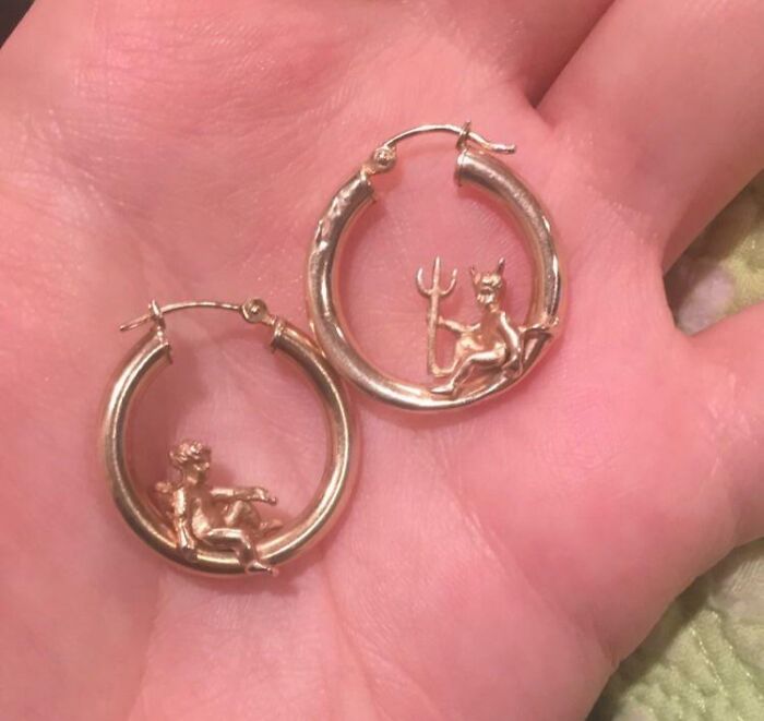 Gold hoop earrings with devil figures inside, shown on a hand, a unique thrift store jackpot find by lucky shoppers
