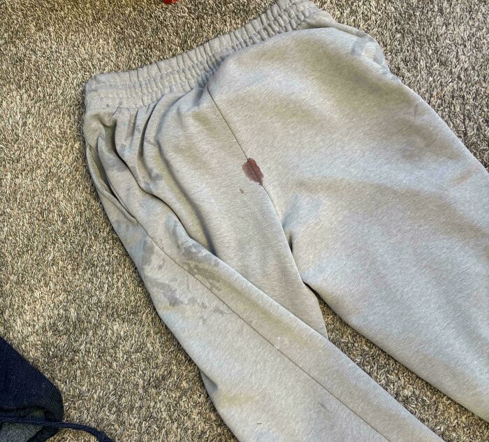 Light gray sweatpants with visible stains lying on a carpet, illustrating wild People of Walmart fashion moments.