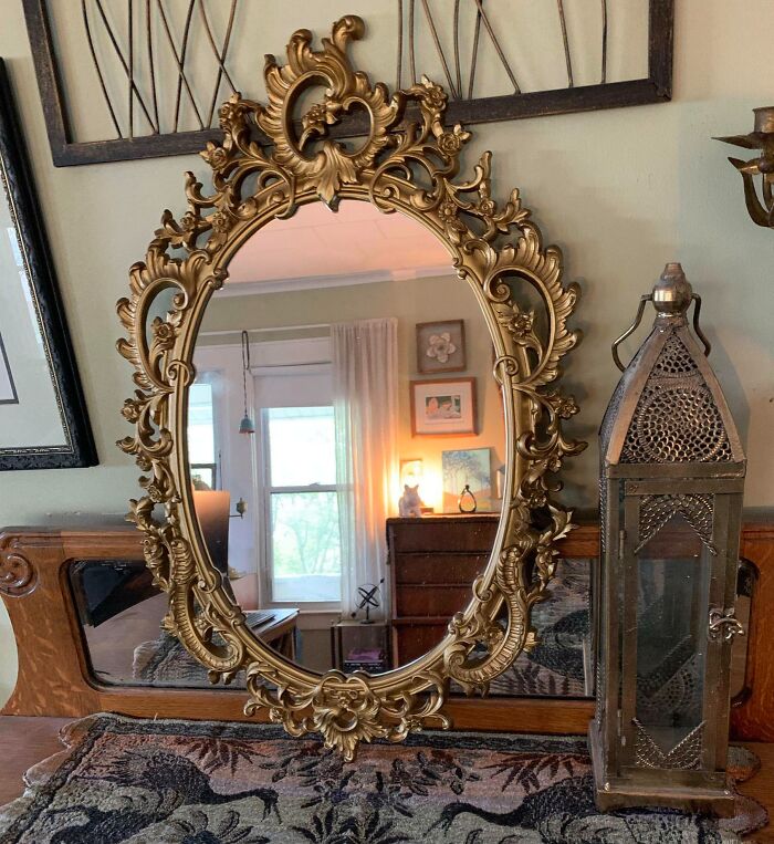 Ornate vintage gold mirror and antique metal lantern on a wooden surface showcasing thrift store jackpot finds.
