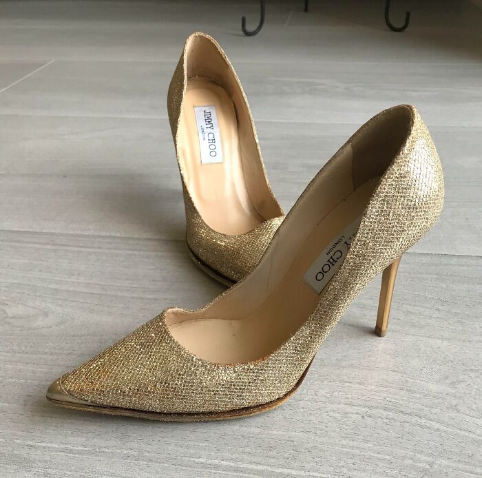 Pair of gold high heel Jimmy Choo shoes on wooden floor, a thrift store jackpot find for lucky shoppers
