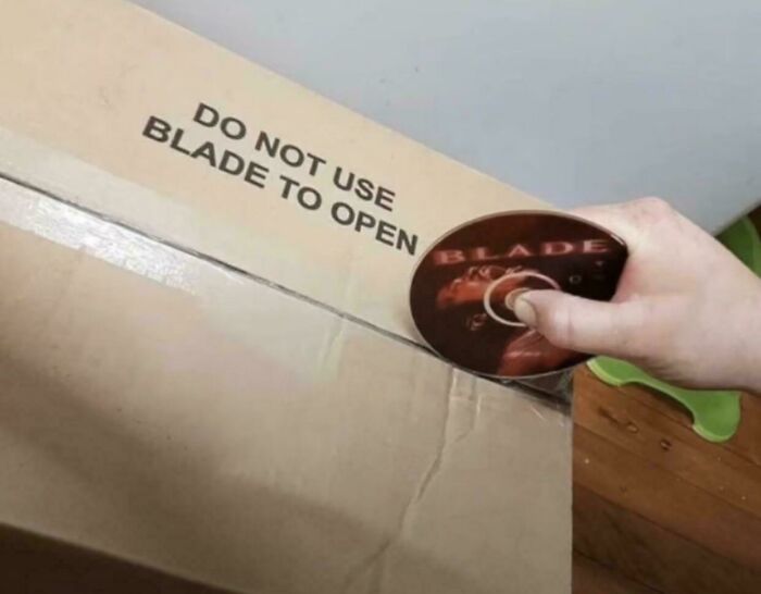 Hand using a Blade DVD to open a box with the warning not to use a blade, humorous picture that goes hard.