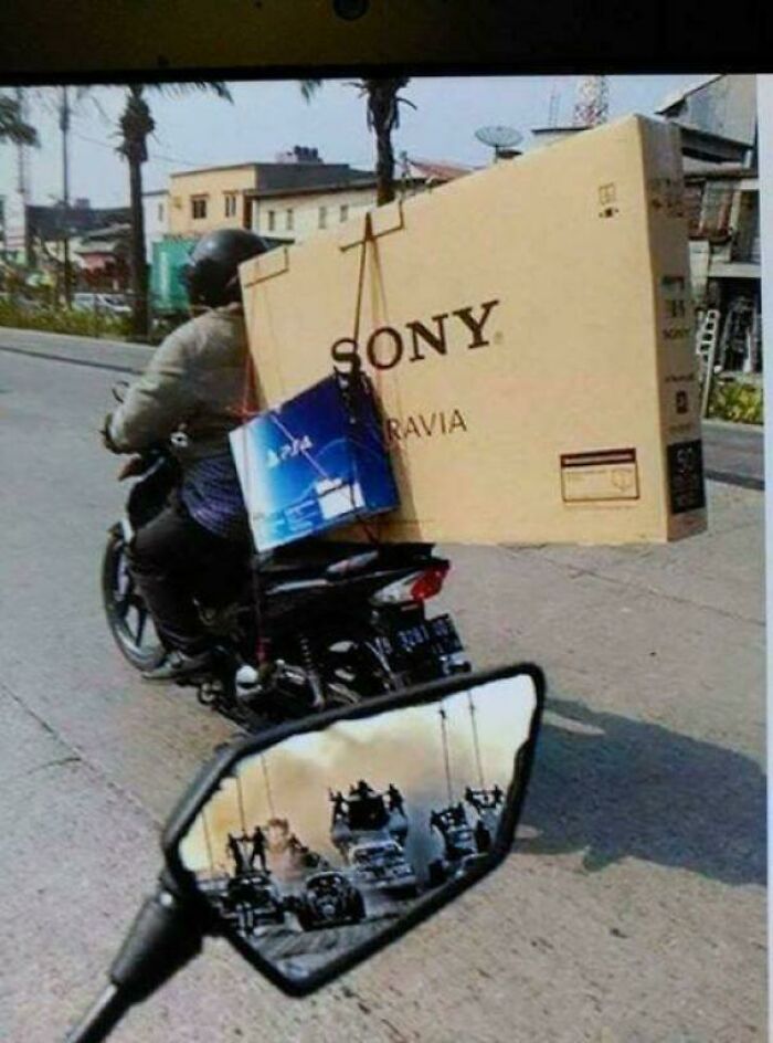 Person on motorcycle carrying large Sony TV and PS4 box, illustrating one of the funniest pictures that go hard online.