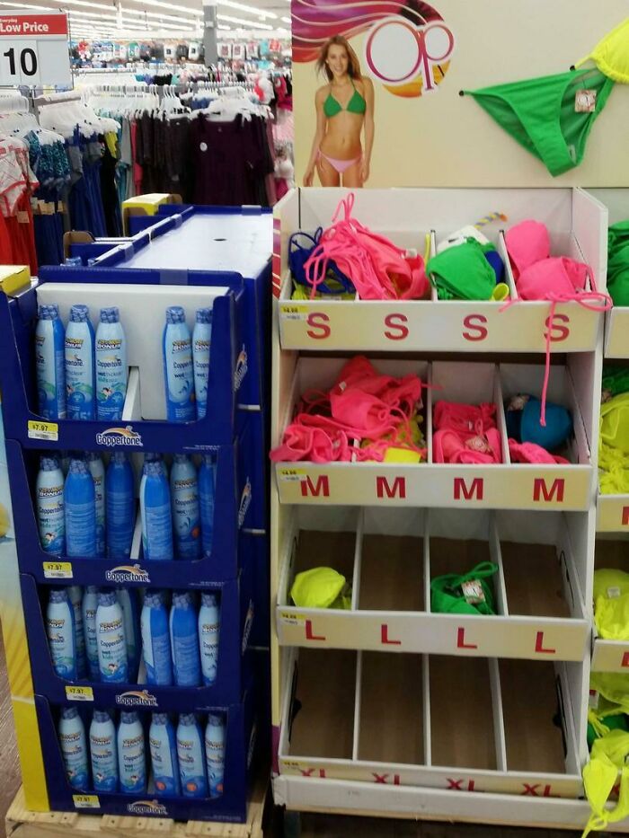 Colorful women’s swimwear and sunscreen display shelves in a Walmart store aisle showing chaotic stock organization.