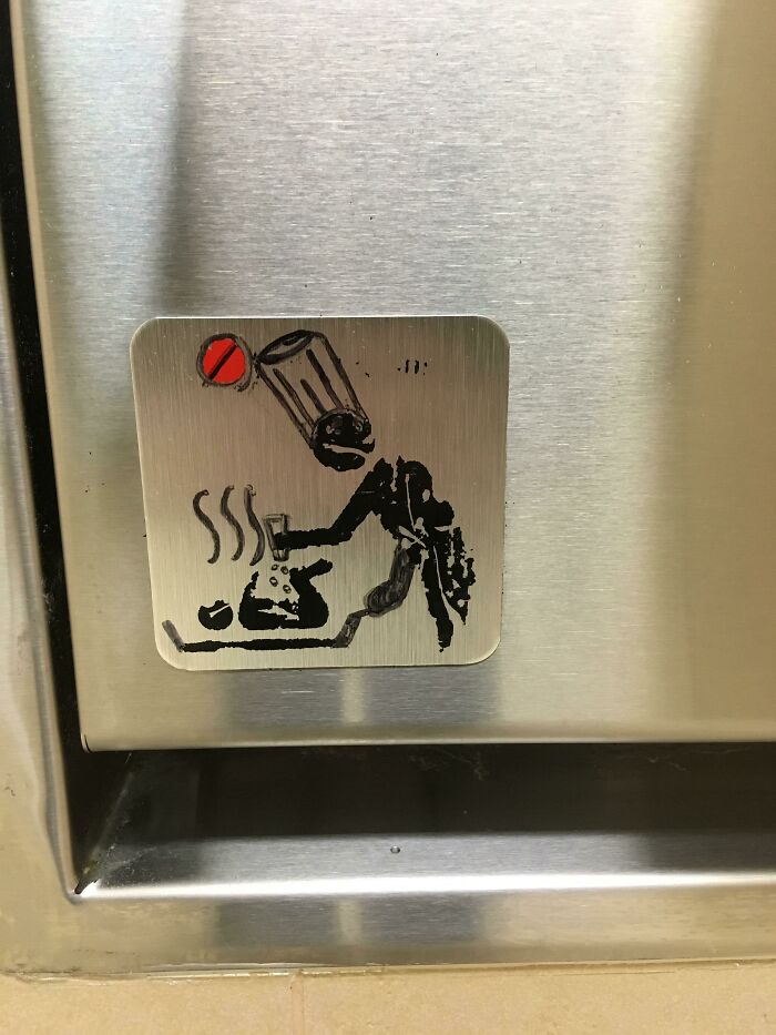 Sticker of a person tipping over a trash can onto a steaming cup, humorous people of Walmart style sign on metal surface.