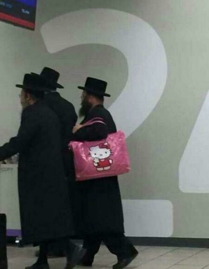 Three men wearing black hats and coats, one carrying a bright pink Hello Kitty bag, humorous pictures that go hard.