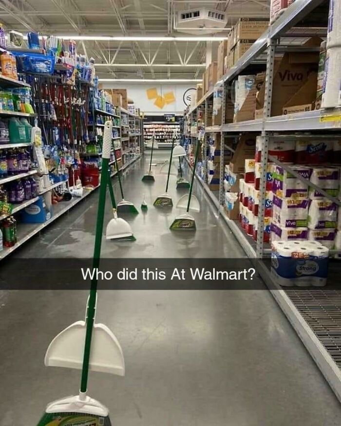 Brooms and dustpans standing upright in a Walmart aisle, creating a humorous and unusual store scene.