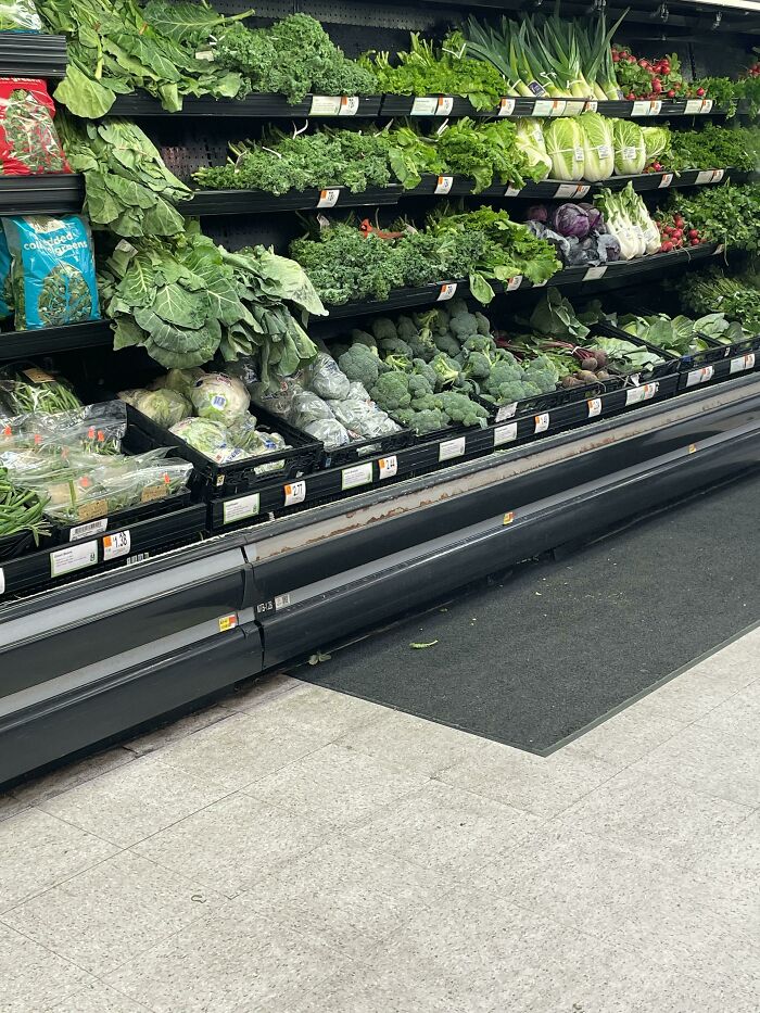 Fresh green vegetables displayed in a Walmart produce section showcasing a variety of leafy greens and broccoli.