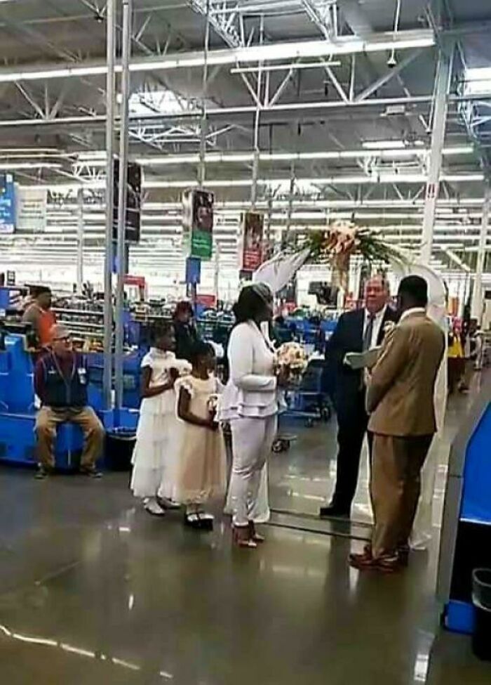 Wedding ceremony taking place inside a Walmart store with bride, groom, and flower girls in formal attire.