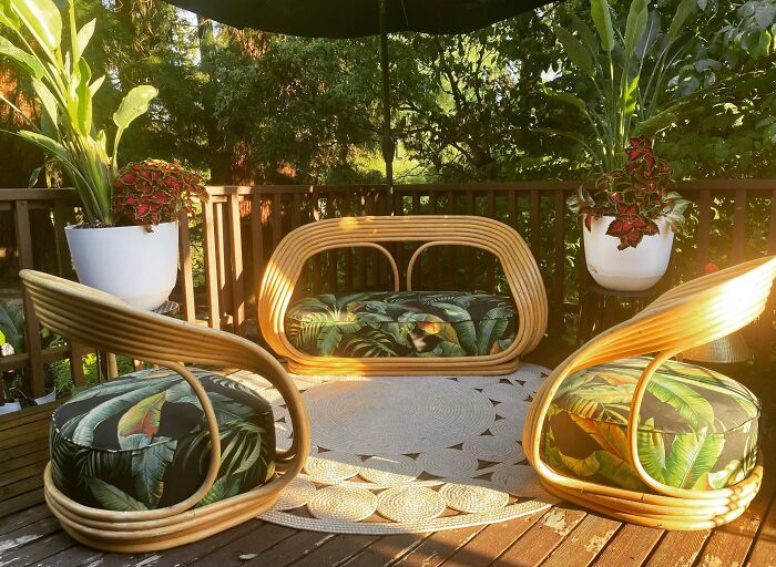 Rattan patio furniture with tropical cushions on a wooden deck surrounded by plants in a thrift store jackpot find.
