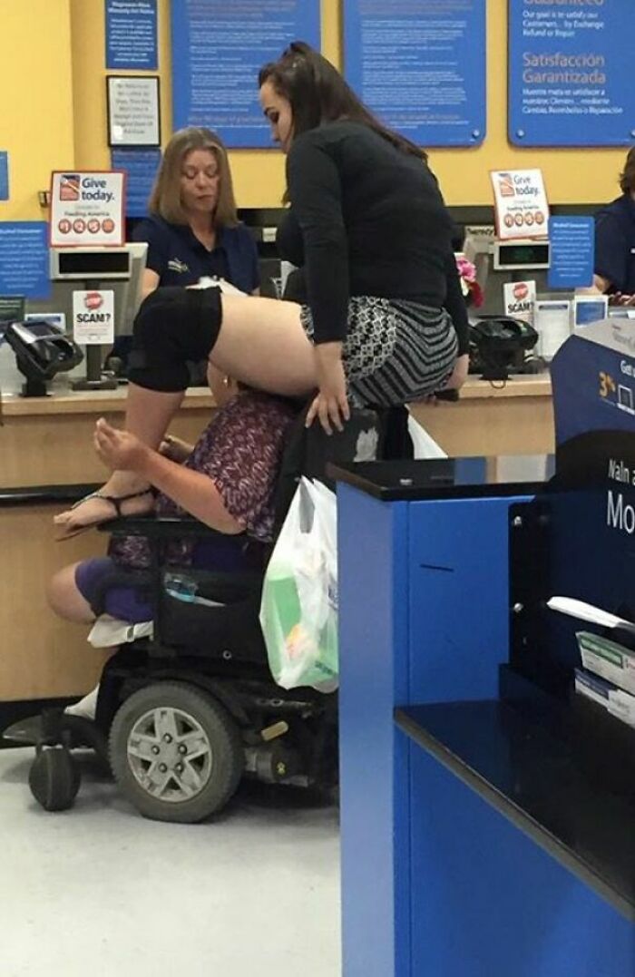 Woman sitting on a man in a wheelchair at a Walmart checkout counter in a humorous People of Walmart moment.