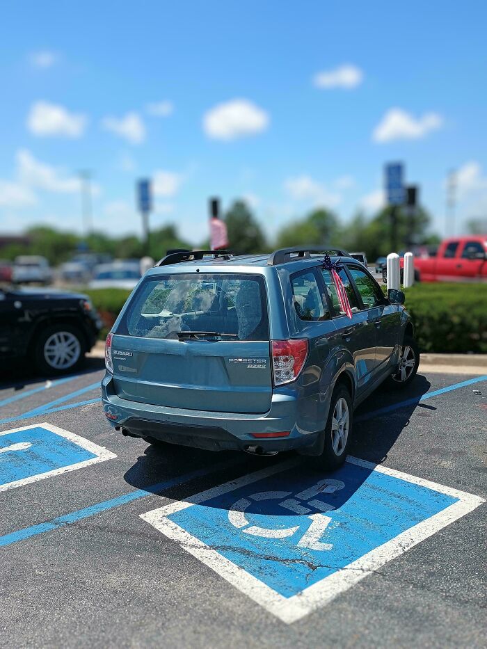 Blue Subaru Forester parked incorrectly in a handicapped spot, highlighting unusual People of Walmart behavior in a parking lot.