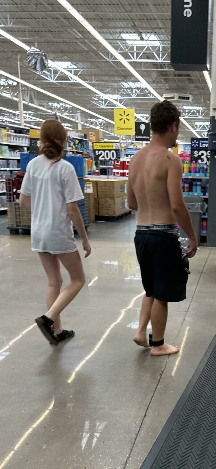 Two people walking inside Walmart, one shirtless and barefoot, showcasing unusual behavior in People of Walmart pics.