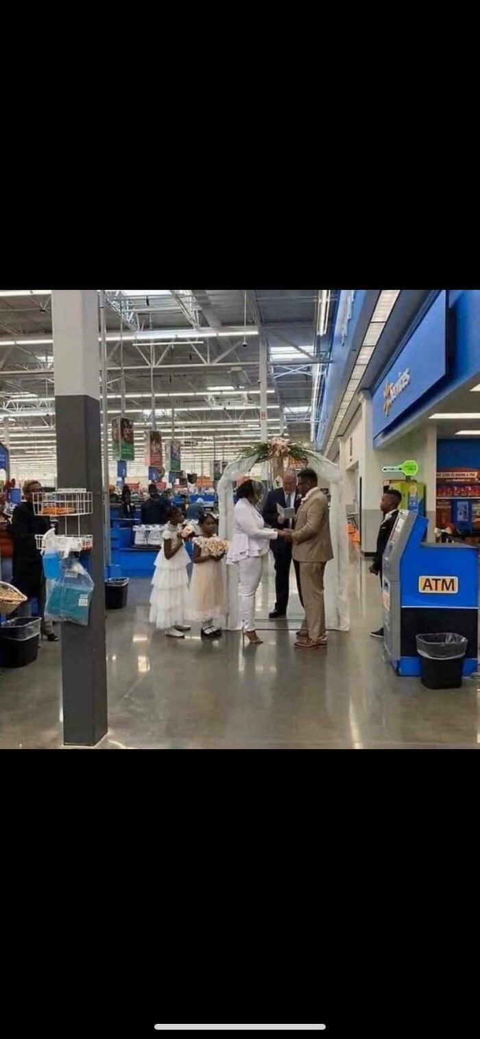 Couple exchanging vows in a Walmart store aisle with flower girls and an officiant during a unique wedding ceremony.