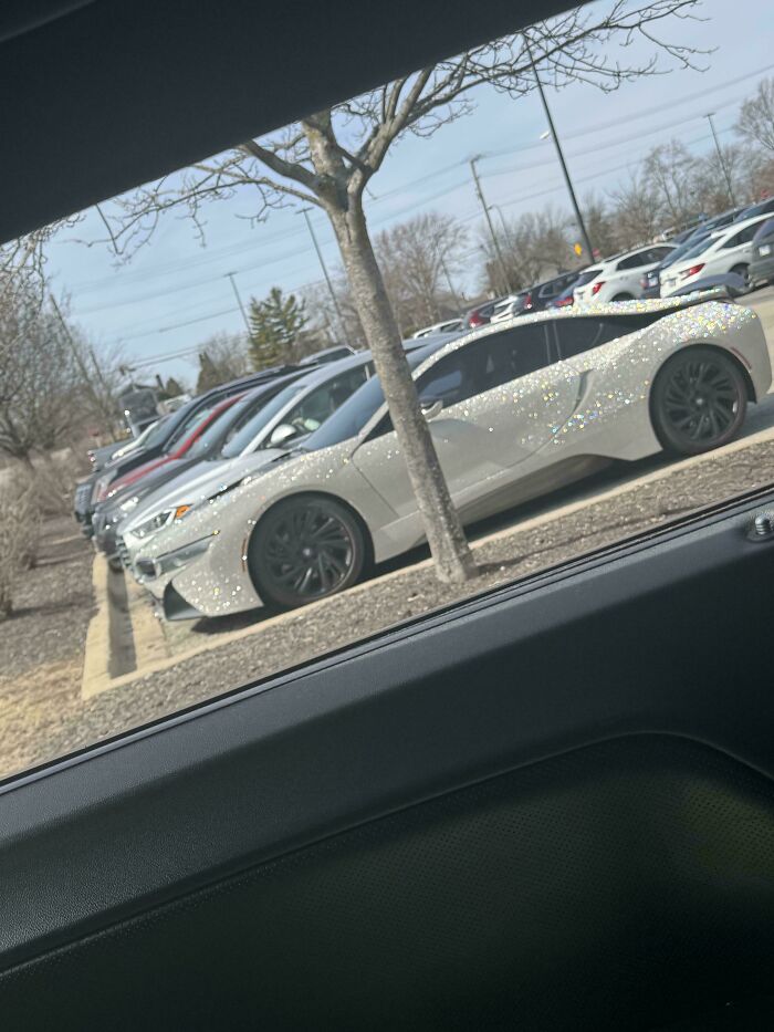 Shiny luxury car covered in sparkling rhinestones parked in a lot, illustrating unique people of Walmart style.