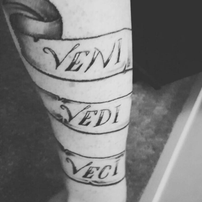 Tattoo fail with misspelled Latin phrase on leg in a black ink ribbon style, showcasing an epic tattoo fail example.