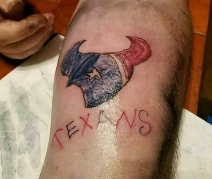 Tattoo fail of a misspelled Texans logo with uneven design and coloring on a person's leg.