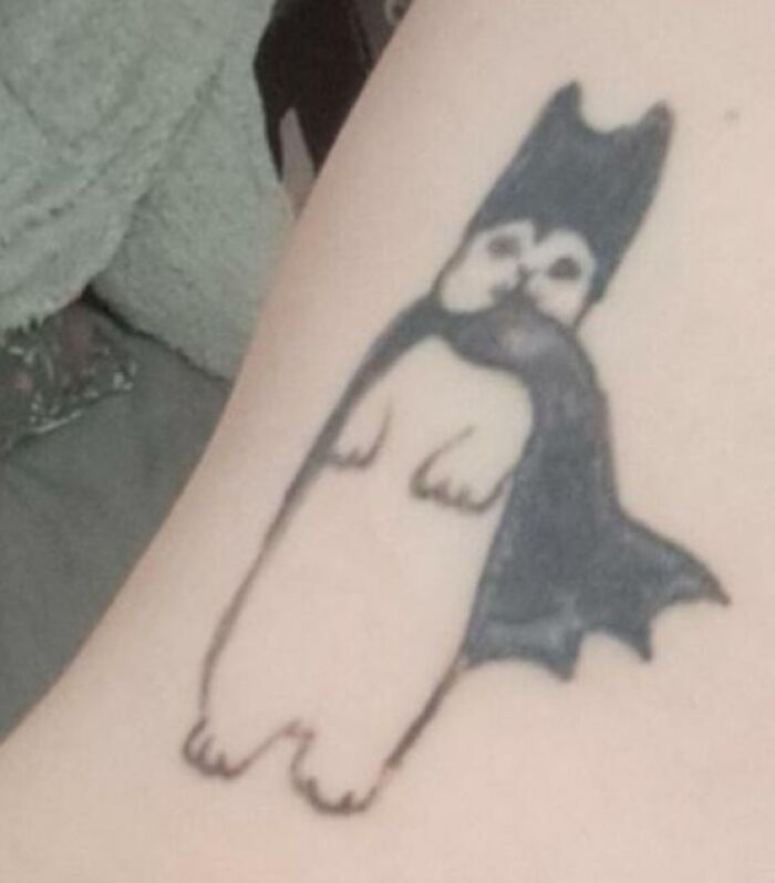 Tattoo fail showing a poorly drawn Batman costume on a small animal, blending comedic and epic tattoo fails.