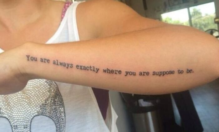 Tattoo fail showing a misspelled quote on a forearm with black typewriter-style font on light skin.