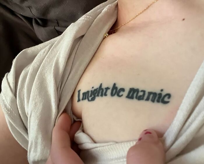 Tattoo fail showing a misspelled phrase on a person's chest with a beige shirt partially covering the skin.