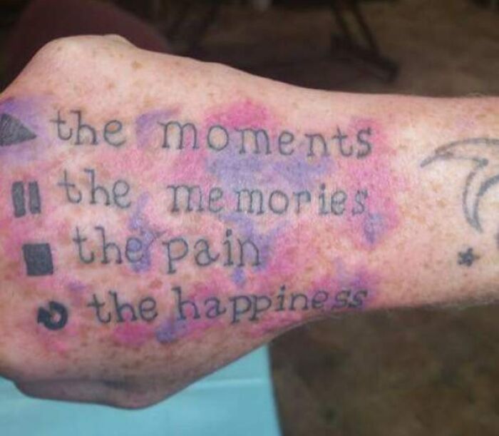 Close-up of an arm with an epic tattoo fail featuring text and symbols with smudged ink and discoloration.