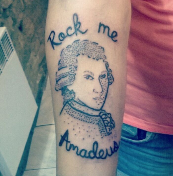 Tattoo fail of a poorly drawn Mozart portrait with the words Rock me Amadeus on a forearm.