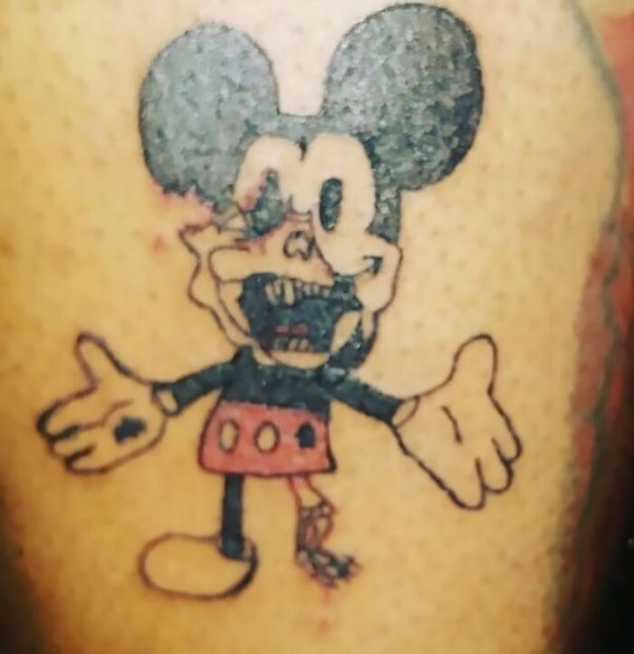 Poorly executed tattoo fail of a cartoon character with distorted features and uneven lines on skin.