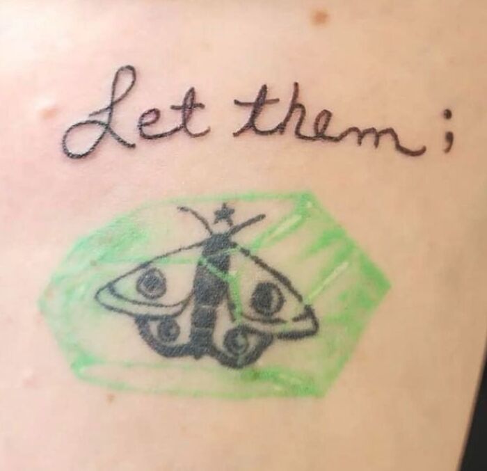 Tattoo fail showing a poorly drawn butterfly and the phrase let them with a semicolon on skin.