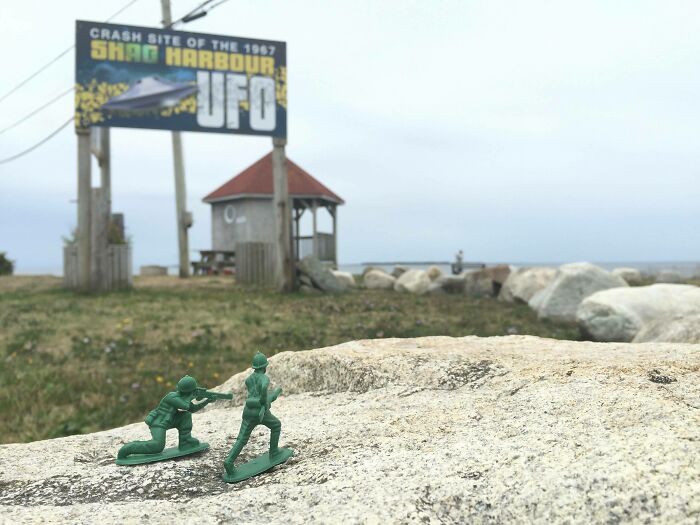 Two green toy soldiers on a rock near a UFO crash site sign, illustrating weird and suspicious things that happened in the ocean.
