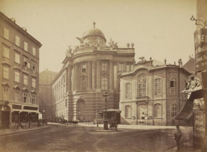 Historic photo showing a world capital city street scene with classical architecture from before modern times.