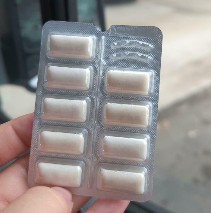 Hand holding a blister pack of white chewing gum tablets as an example of sneakflation in everyday products.