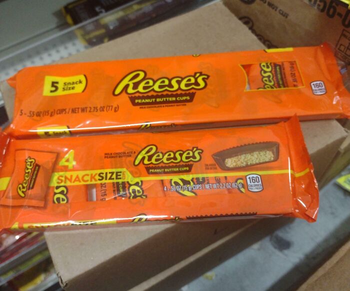 Two different snack size packages of Reese's peanut butter cups stacked on a box, illustrating sneakflation examples.