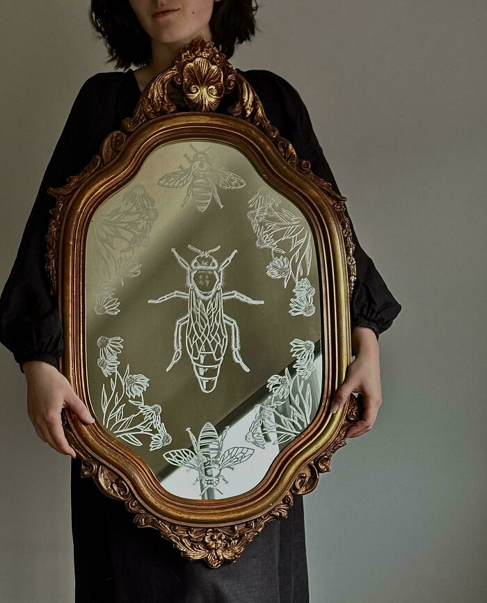 Person holding ornate vintage mirror with engraved bees and floral designs, showcasing cottage core aesthetics.
