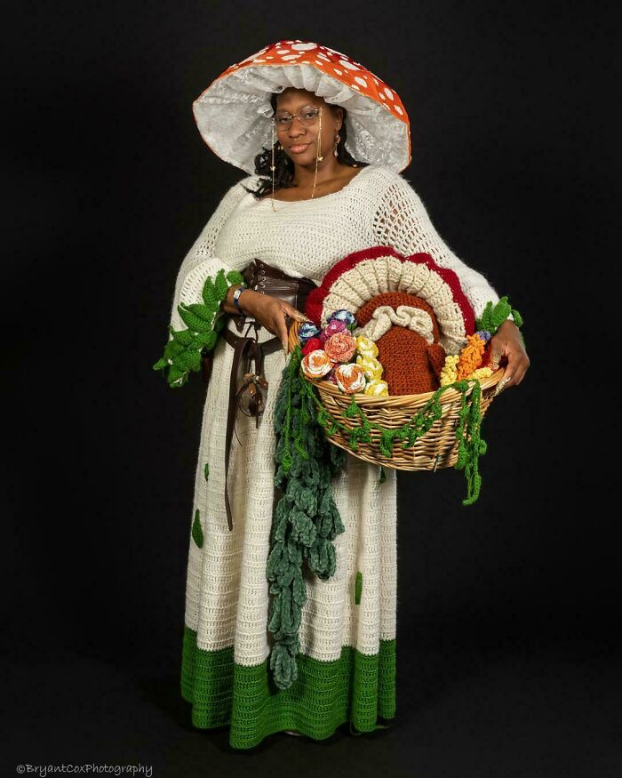 Woman in a cottage core aesthetics inspired crochet dress and mushroom hat holding a basket of crocheted flowers.