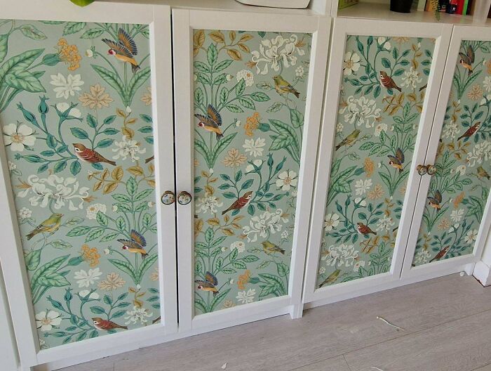 White cabinets featuring cottage core aesthetics with floral and bird patterns on a pastel green background.